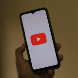 Close-up of a smartphone displaying the YouTube app logo on the screen.